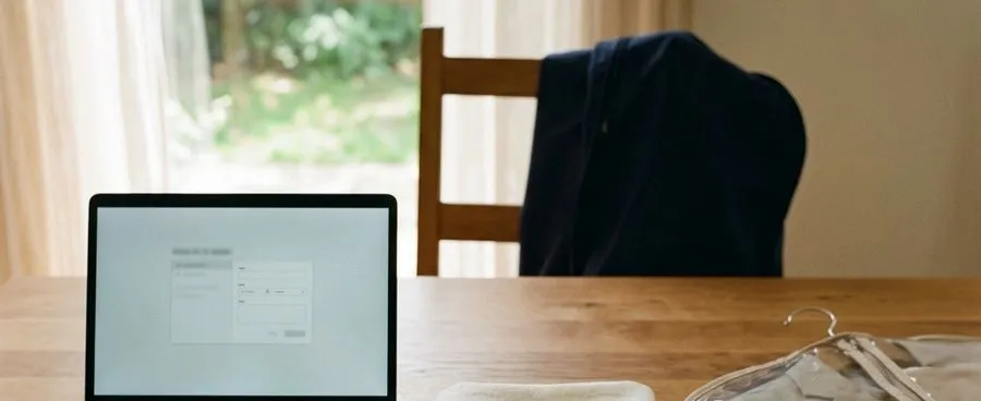 A laptop, a fabric swatch and a garment bag together on a desk, representing three wedding-attire tracks planned from one date