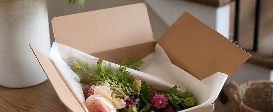 A single flower-subscription box opened on a home entryway table.