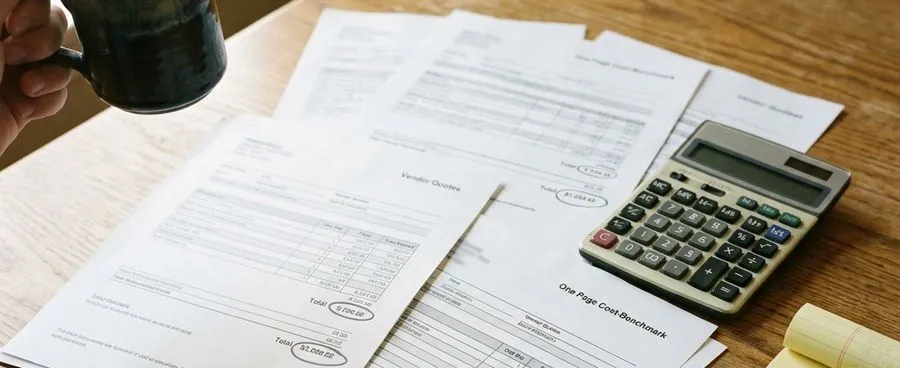 Vendor quotes and wedding cost benchmarks with different totals circled, next to a calculator and legal pad