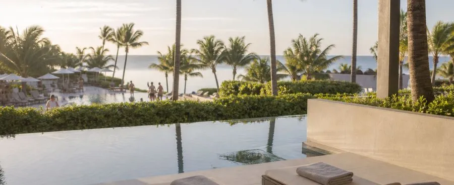 A quiet adults-only pool terrace at an all-inclusive resort, separated from the family pool area by a hedge line.