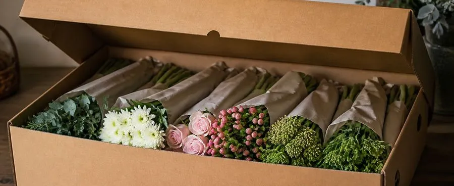 An opened wholesale flower shipping box with bundled fresh-cut stems inside.