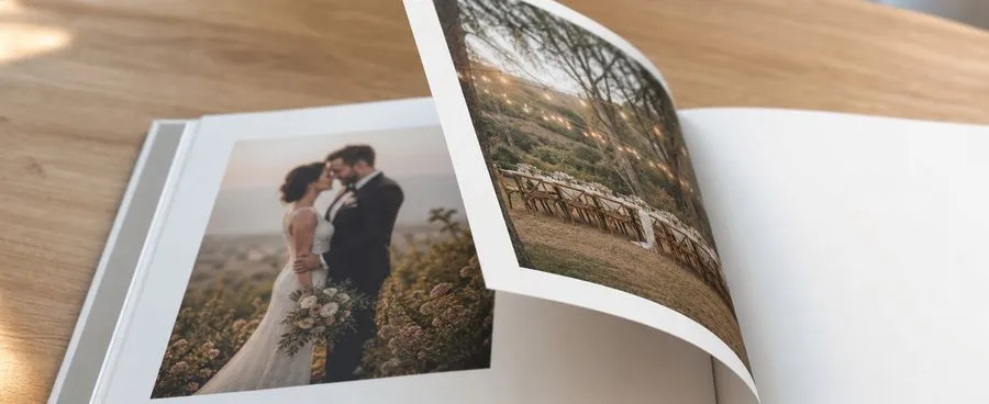 An open Mixbook wedding photo book on a wood table, showing a printed page of wedding photographs.