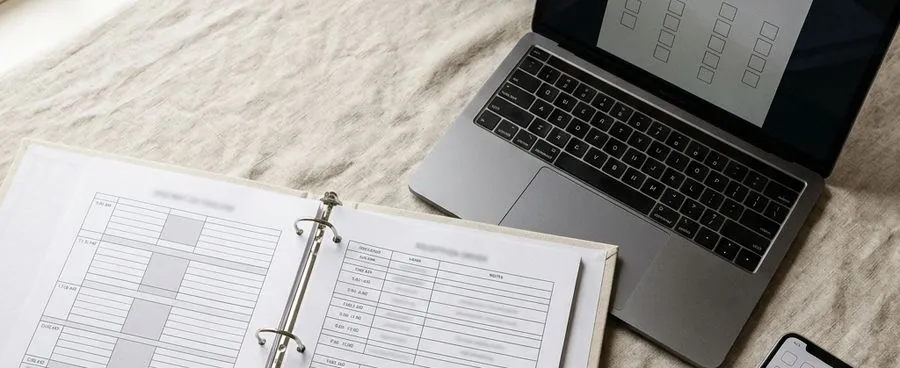 A wedding day-of binder and a laptop with planning software side by side